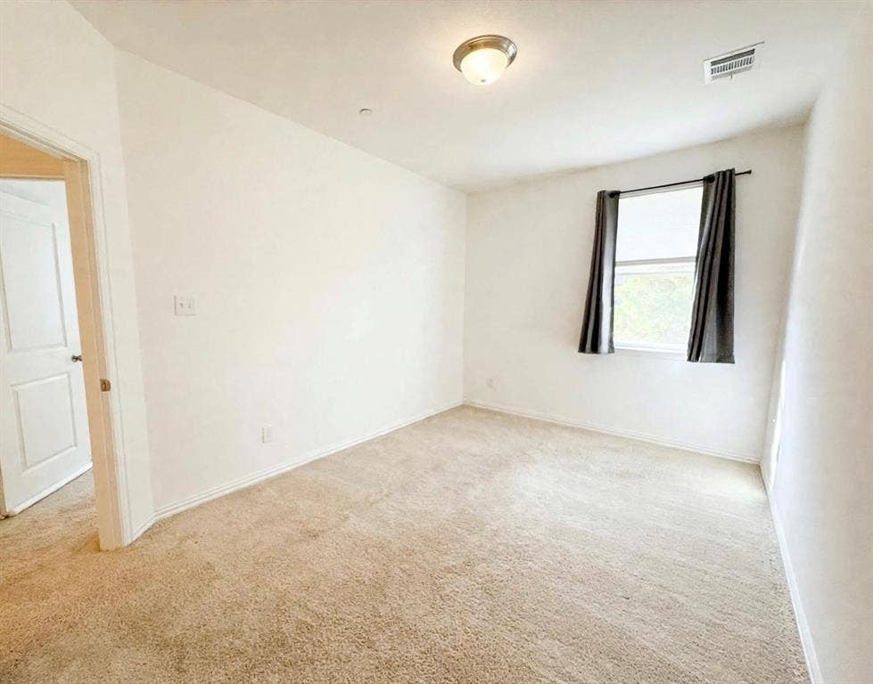 Neutral-toned carpeted flooring, white interior walls, flush-mount ceiling lighting, and a single-pane window
