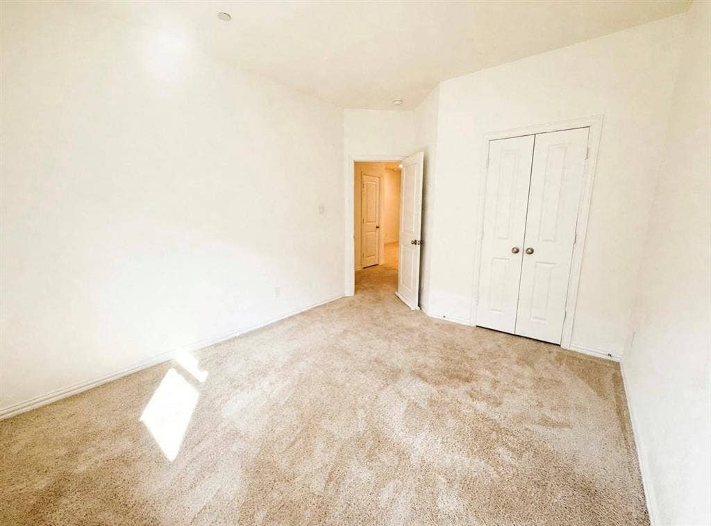 Neutral wall tones, carpeted flooring, and double-panel closet doors featuring brushed metallic hardware