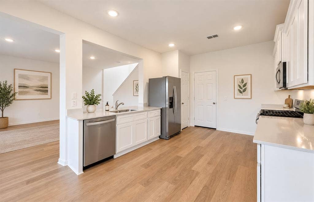 Kitchen featuring white shaker-style cabinetry, neutral stone-composite countertops, stainless steel appliances, recessed lighting, and wood-finish flooring