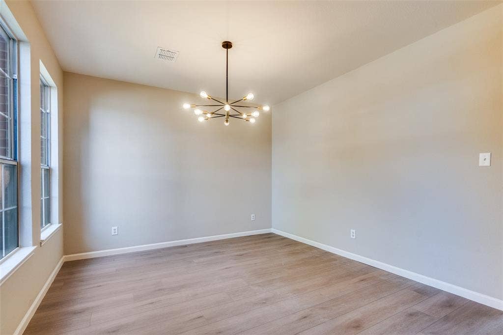 Room featuring wood-finish flooring, dual vertical windows, and a multi-arm sputnik-style chandelier with exposed bulbs