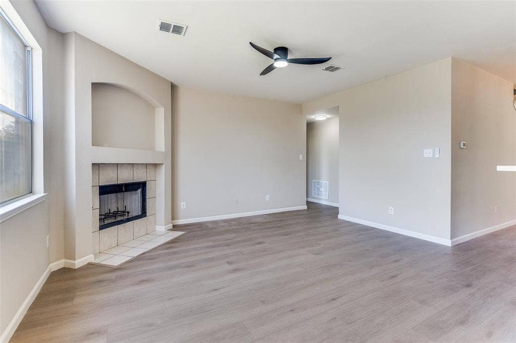 Interior space featuring wood-finish flooring, a recessed fireplace with tile surround, arched architectural niche, and a ceiling-mounted light fixture