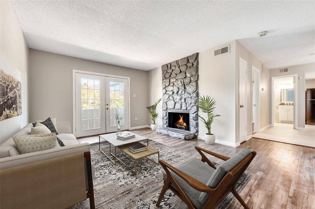 5623 Harvest Hill Road, #2023, Dallas, TX 75230 Living room featuring Wood-look luxury vinyl planks (LVP) , a floor-to-ceiling stone fireplace, and French doors