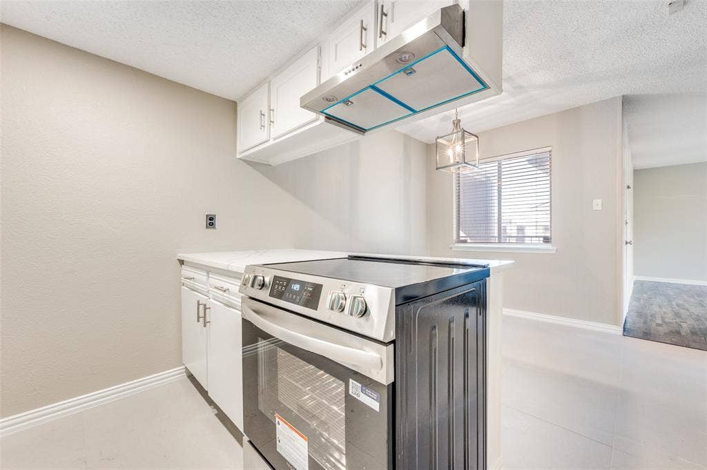 5623 Harvest Hill Road, #2023, Dallas, TX 75230 Kitchen featuring white cabinetry, stainless steel range, mounted stainless steel range hood, and a pendant light fixture