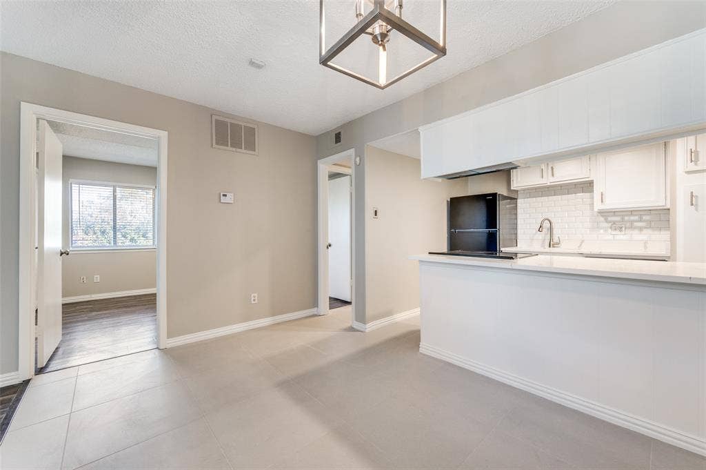 5623 Harvest Hill Road, #2023, Dallas, TX 75230 Kitchen featuring white cabinetry, subway tile backsplash, quartz countertops, and geometric lantern-style ceiling lighting, complemented by tile flooring