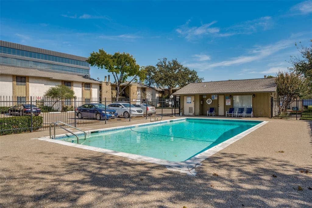 5623 Harvest Hill Road, #2023, Dallas, TX 75230 In-ground swimming pool with a concrete deck, metal perimeter fencing, and an adjacent community building