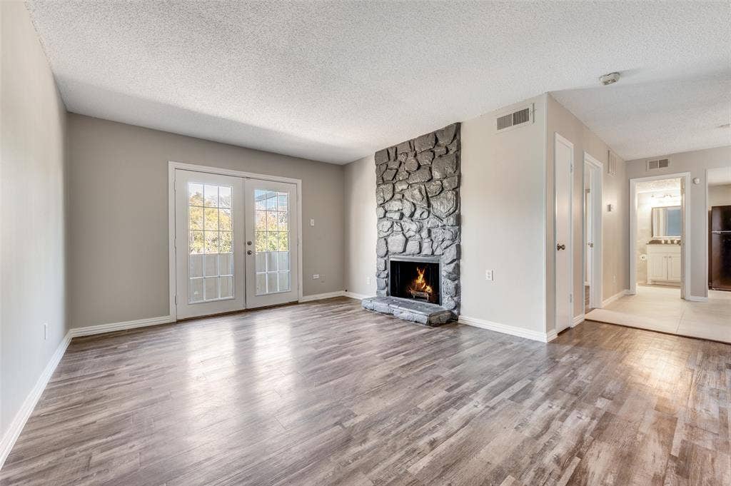 5623 Harvest Hill Road, #2023, Dallas, TX 75230 Living space featuring Wood-look luxury vinyl planks (LVP) , and tone-veneer fireplace with raised hearth, and double French doors