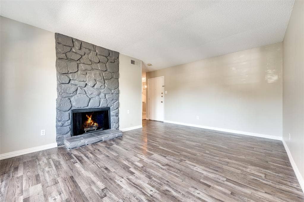 5623 Harvest Hill Road, #2023, Dallas, TX 75230 Living area featuring Wood-look luxury vinyl planks (LVP) and a floor-to-ceiling hearth with grey stone masonry and a raised stone hearth