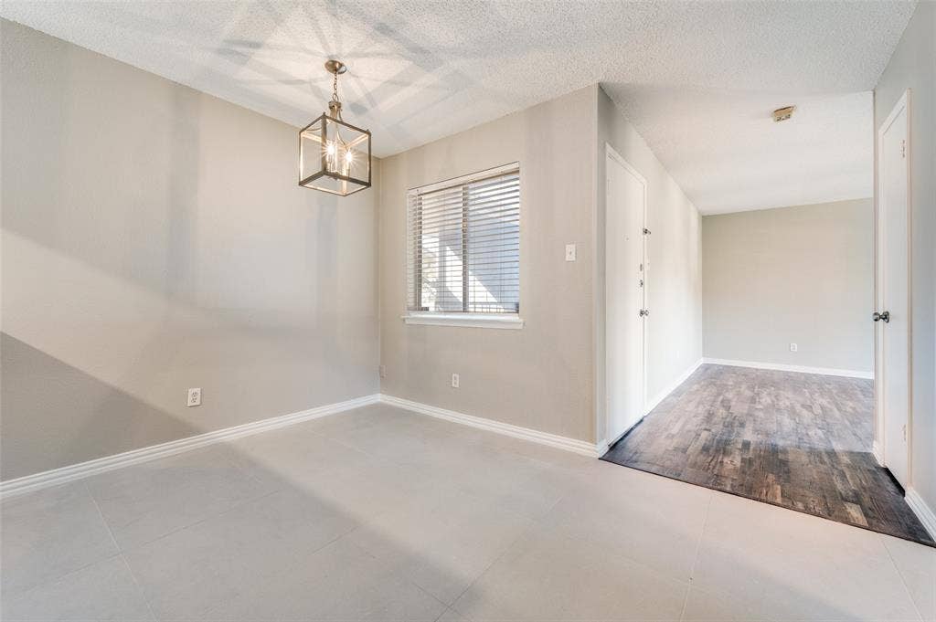 5623 Harvest Hill Road, #2023, Dallas, TX 75230 Neutral-toned interior featuring large-format ceramic tile flooring, a geometric metal lantern pendant light, and dark wood-finish flooring