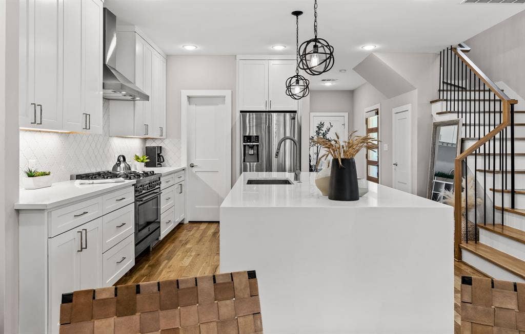 406 Parkview Avenue, Dallas, TX 75223 Kitchen featuring stainless steel refrigerator with ice dispenser, light hardwood / wood-style flooring, an island with sink, wall chimney exhaust hood, and range with gas cooktop