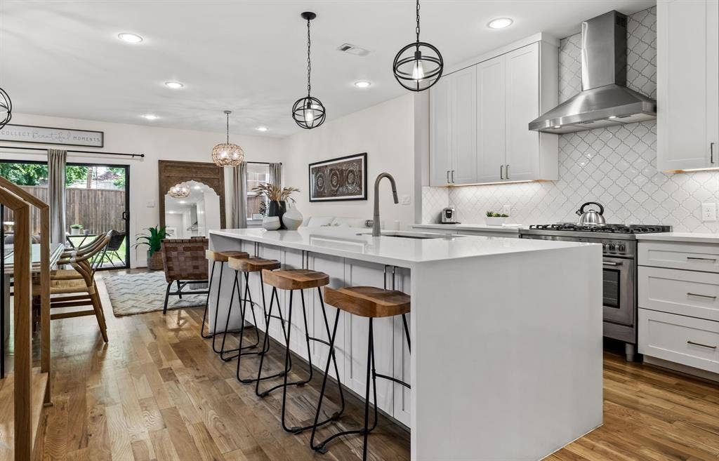 406 Parkview Avenue, Dallas, TX 75223 Kitchen featuring an island with sink, light wood-type flooring, stainless steel stove, wall chimney exhaust hood, and sink