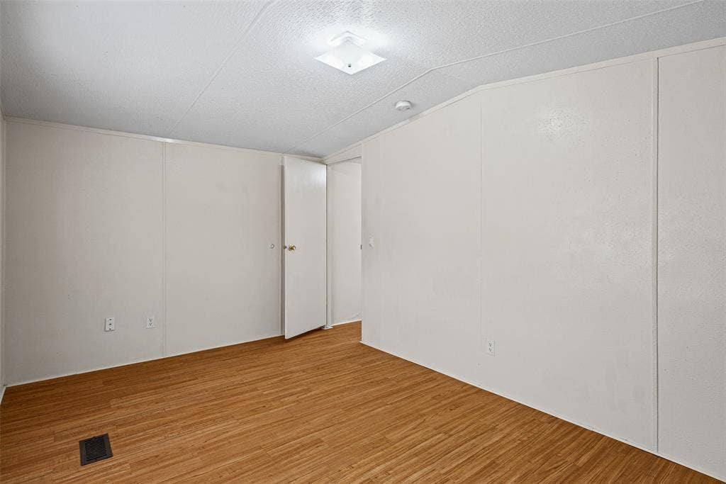 Interior room featuring wood-finish flooring, smooth white walls, and a central square flush-mount light fixture