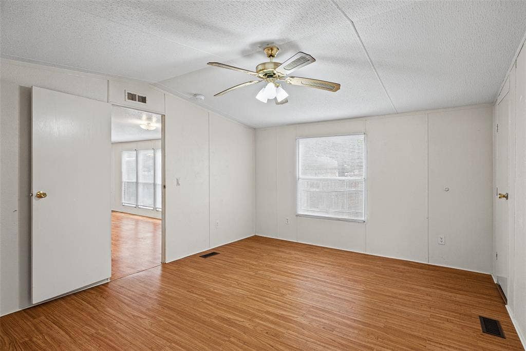 Interior room featuring wood-finish flooring, a ceiling fan with integrated lighting, and a single-pane window