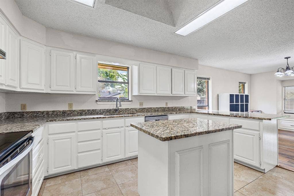 1307 Edna Street, Commerce, TX 75428 Kitchen featuring white cabinetry, stone-surface countertops, center island, tile flooring, and recessed ceiling lighting