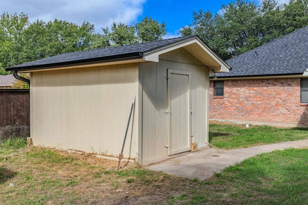1307 Edna Street, Commerce, TX 75428 Detached storage structure featuring a gable roof, composite shingle roofing, and a concrete foundation