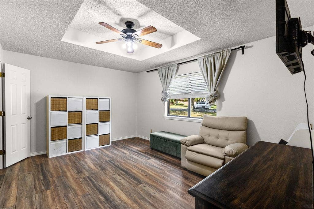 1307 Edna Street, Commerce, TX 75428 Room featuring wood-finish flooring, a tray ceiling, and a central ceiling fan with integrated lighting