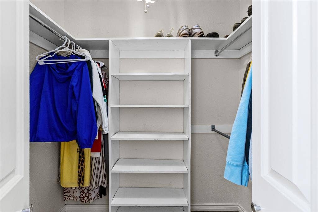 1307 Edna Street, Commerce, TX 75428 Walk-in closet featuring white built-in shelving, dual hanging rods, and an overhead shelf