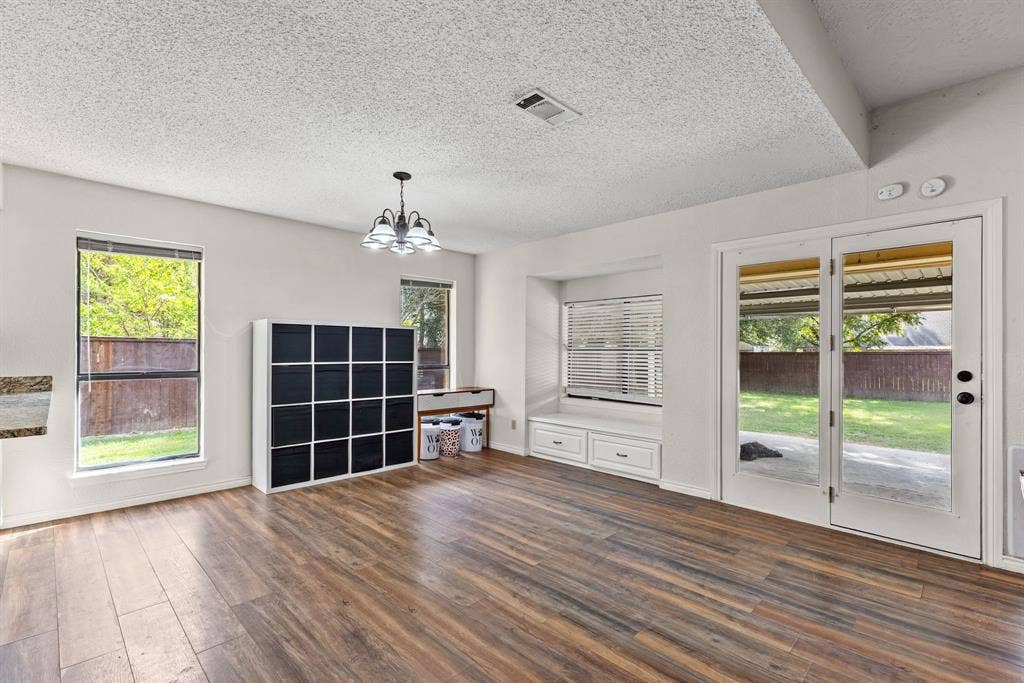 1307 Edna Street, Commerce, TX 75428 Wood-finish flooring, built-in window seating with cabinetry storage, double French doors, and multi-light chandelier fixture