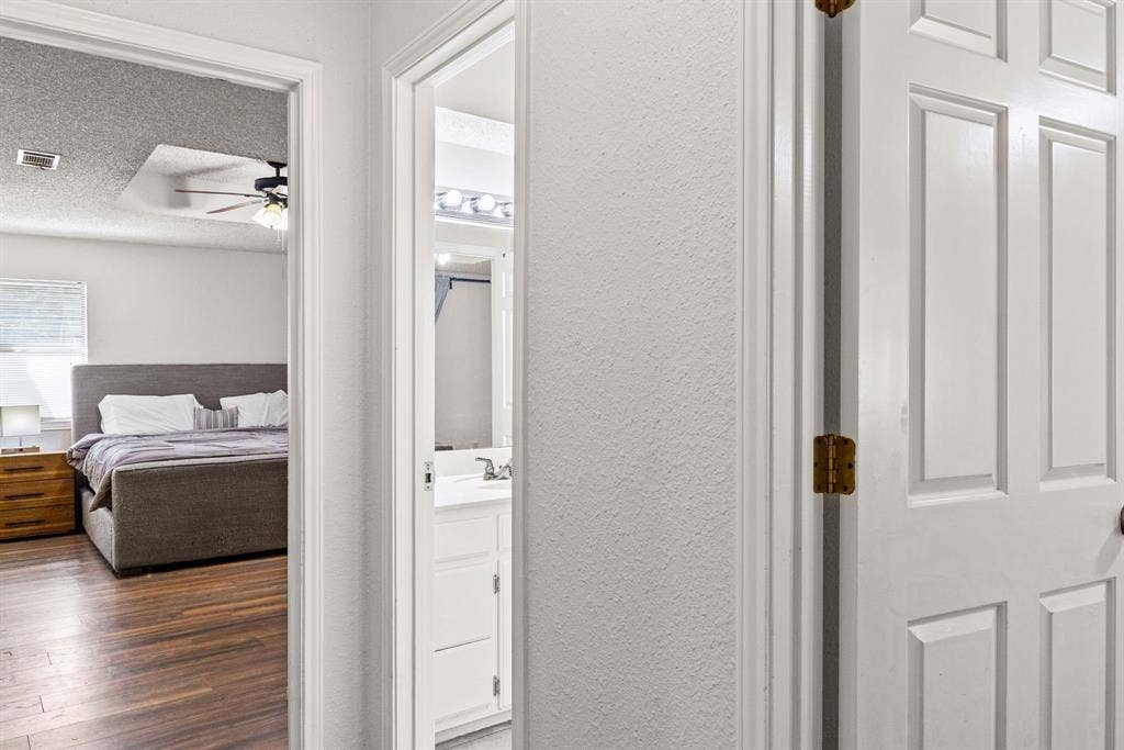 1307 Edna Street, Commerce, TX 75428 White six-panel interior doors, wood-finish flooring, and white vanity cabinetry with a rectangular basin