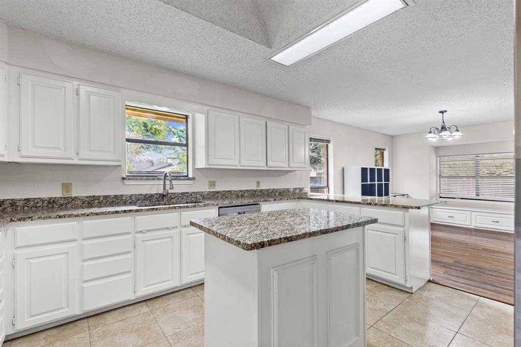 1307 Edna Street, Commerce, TX 75428 Kitchen featuring stone countertops, white shaker-style cabinetry, a central island, recessed ceiling lighting, and tile flooring