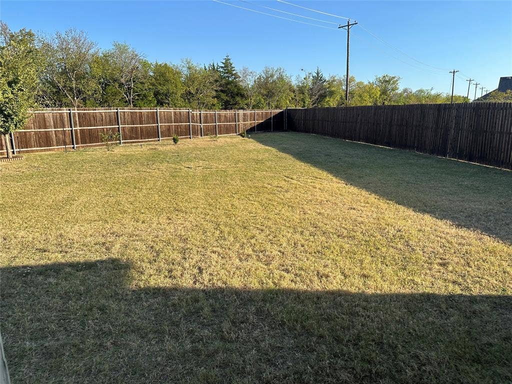 Expansive backyard featuring a level lawn and a full-perimeter wood privacy fence