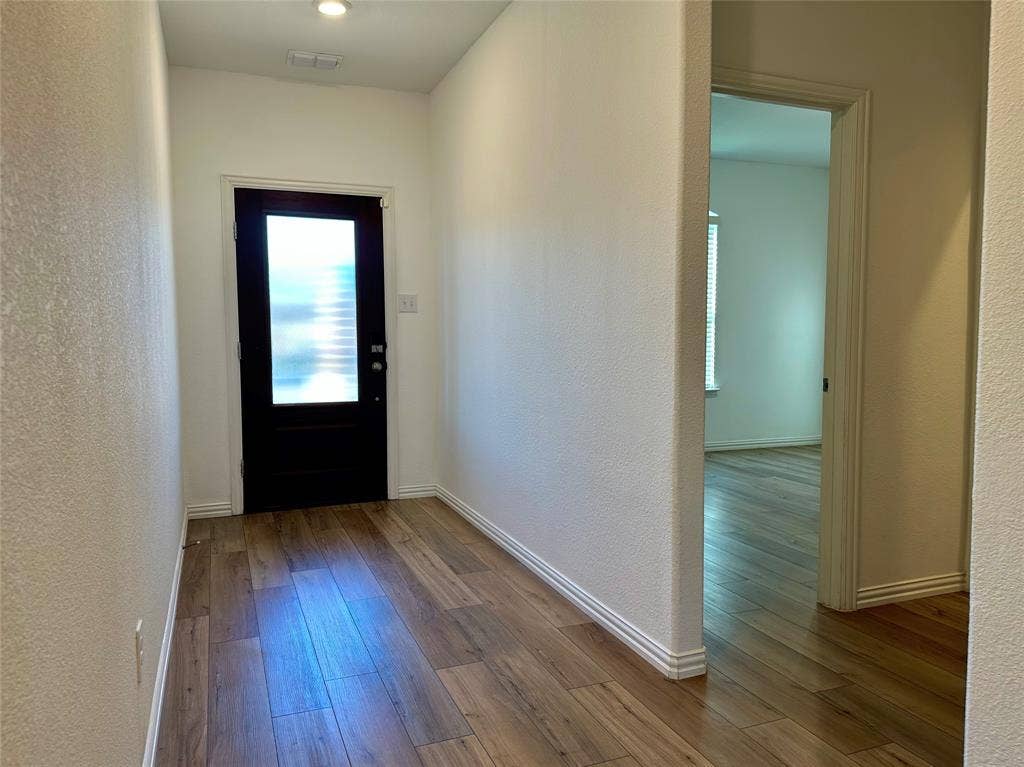 Entryway featuring wood-finish flooring, a solid black front door with a vertical frosted glass panel, and recessed ceiling lighting