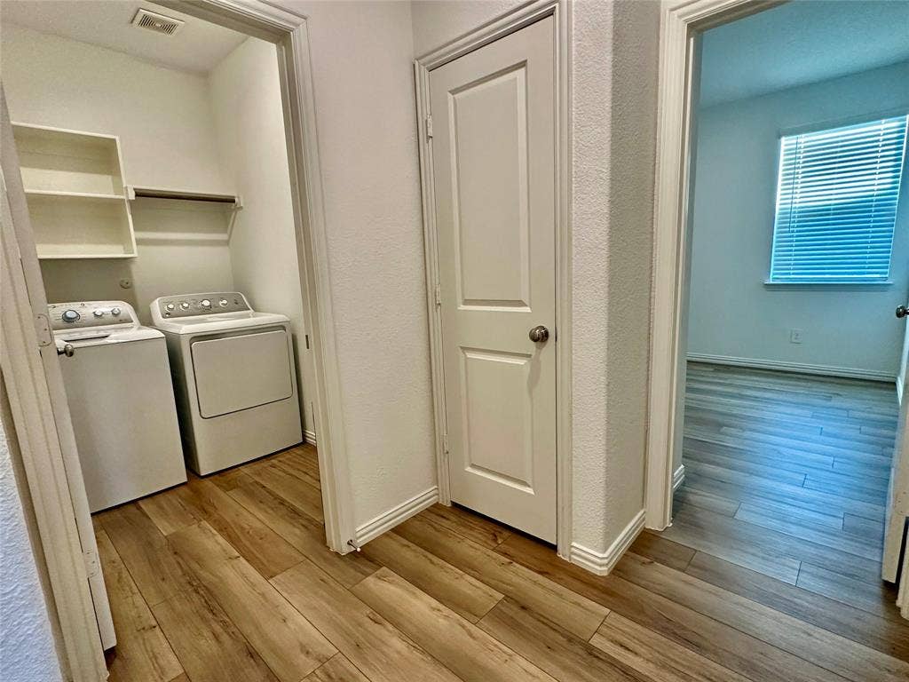 Laundry area featuring wood-finish flooring, built-in shelving, and a paneled interior door