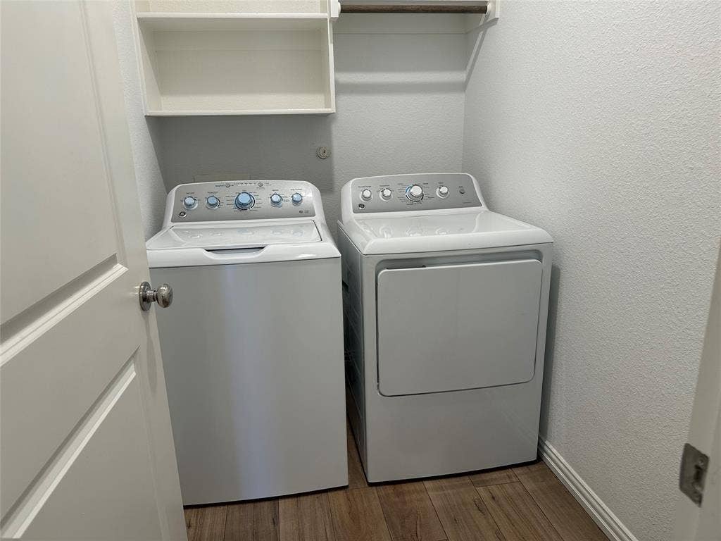 Laundry area featuring wood-finish flooring, white built-in shelving, and a wall-mounted hanging rod