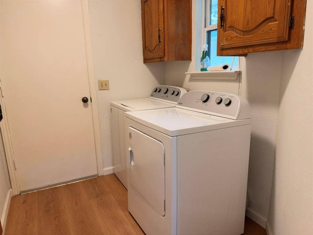 Laundry area featuring wood-finish flooring, overhead wooden cabinetry, and a window ledge