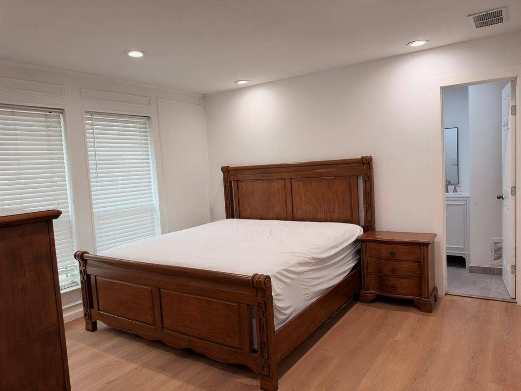 Neutral-toned interior featuring wood-finish flooring, recessed lighting, double windows with horizontal blinds, and paneled wall detailing