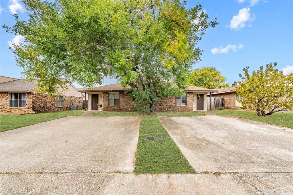 Brick exterior featuring a dual-unit configuration, concrete driveways, and mature landscaping