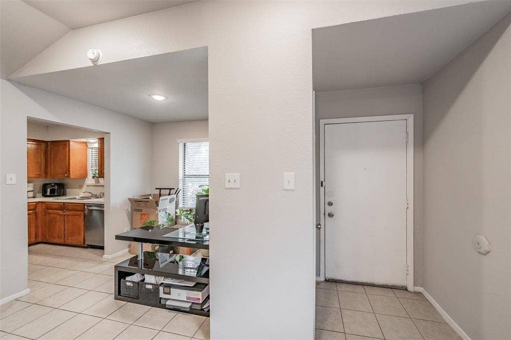 1128 Neutral wall color, ceramic tile flooring, vaulted ceiling, and wood-finish kitchen cabinetry with integrated stainless steel appliances