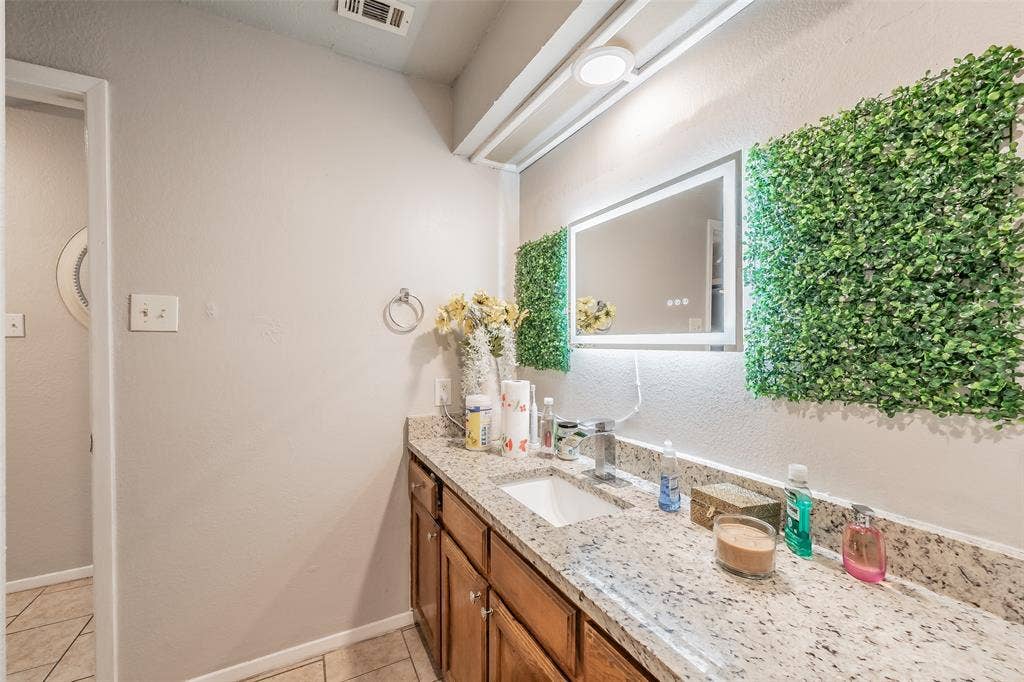 1126 Vanity featuring stone-finish countertop, undermount sink, chrome faucet, and integrated mirror with perimeter illumination