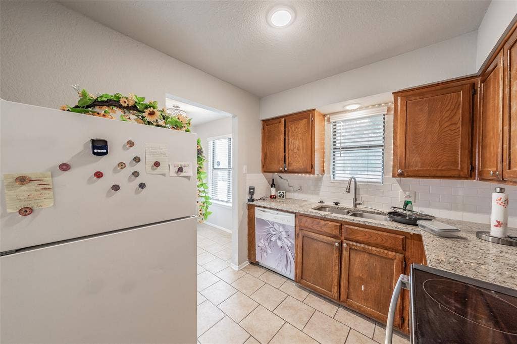 1126 Kitchen featuring medium-toned wood cabinetry, stone-patterned countertops, white subway tile backsplash, and neutral-toned ceramic tile flooring