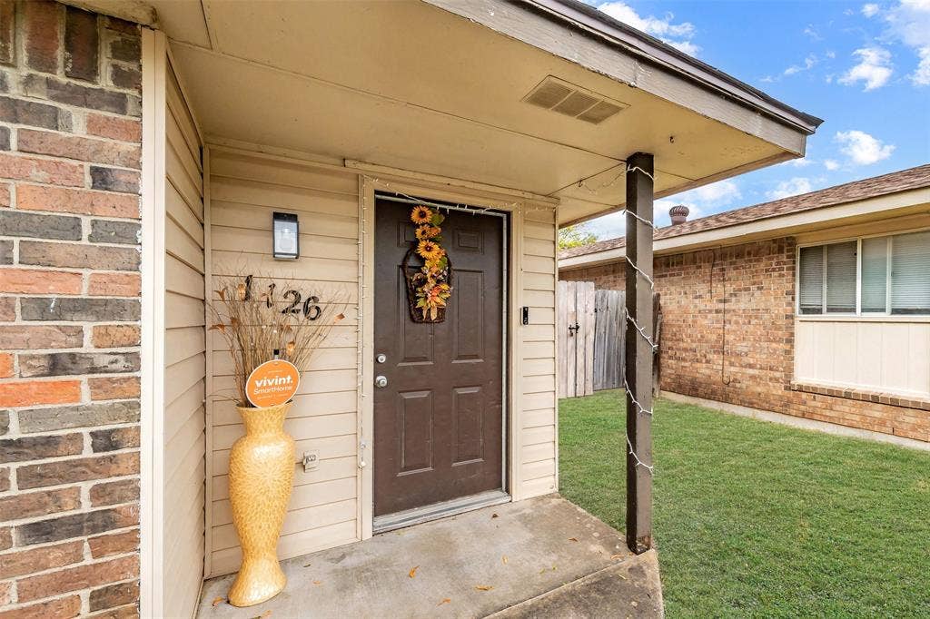 1126 Covered entryway featuring a concrete stoop, horizontal siding, brick exterior facade, and a solid-core front door