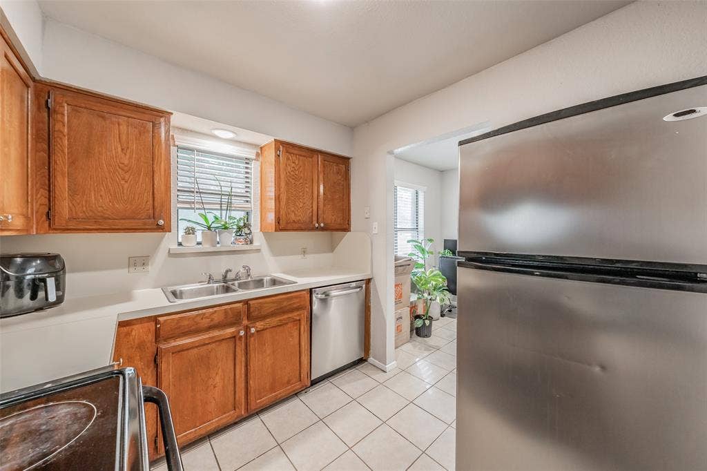 1128 Kitchen featuring wood cabinetry, stainless steel appliances, dual-basin sink, and tile flooring
