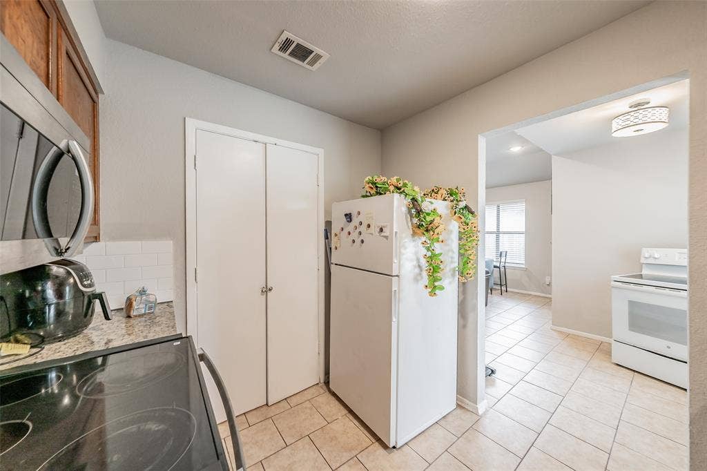 1126 Kitchen featuring stone-finish countertops, white subway tile backsplash, ceramic tile flooring, and built-in closet storage