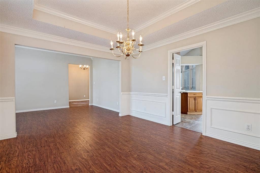1909 Blackfoot Trail, Mesquite, TX 75149 Formal dining area featuring wood-finish flooring, recessed tray ceiling, decorative wainscoting, and a multi-arm brass chandelier