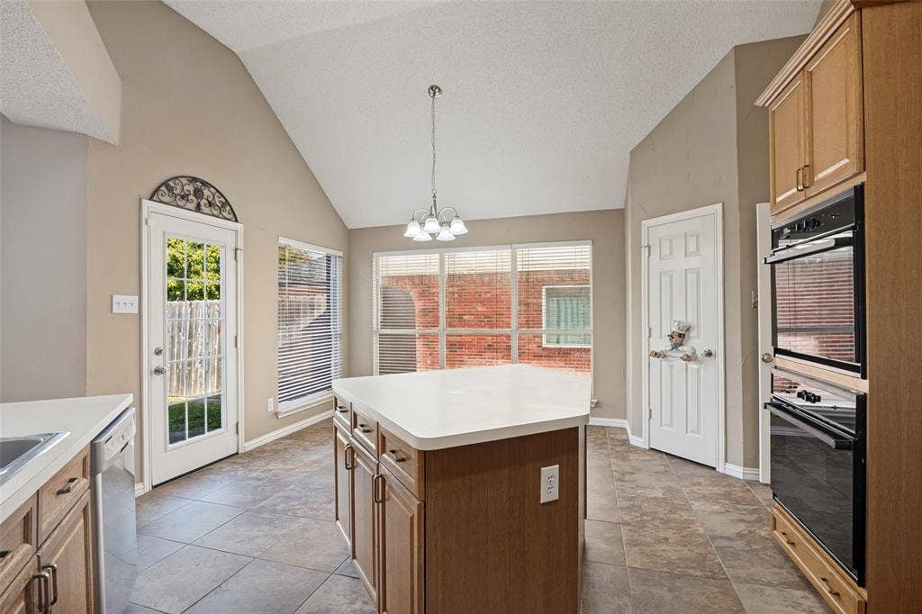 1909 Blackfoot Trail, Mesquite, TX 75149 Vaulted ceiling, center island with solid surface countertop, tile flooring, integrated double wall oven, and a multi-light chandelier