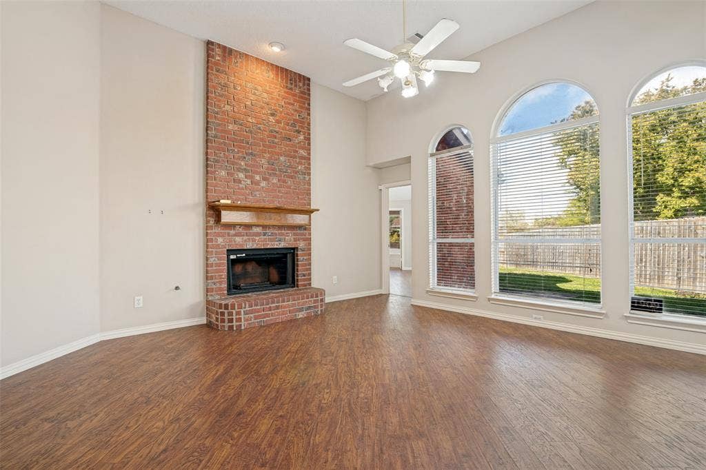 1909 Blackfoot Trail, Mesquite, TX 75149 Floor-to-ceiling red brick fireplace with a wood mantel, high vaulted ceilings, wood-finish flooring, and arched windows