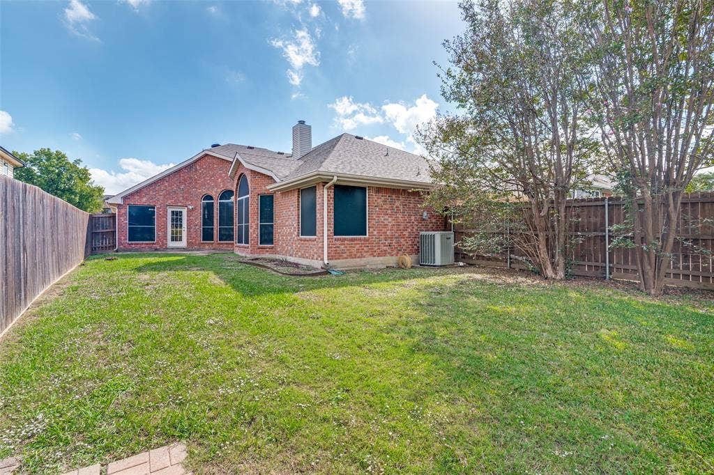 1909 Blackfoot Trail, Mesquite, TX 75149 Brick exterior featuring arched windows, a hipped roofline, and an expansive fenced backyard with mature trees