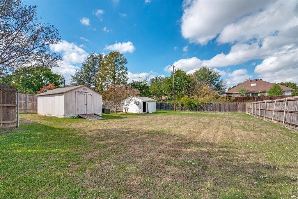 1909 Blackfoot Trail, Mesquite, TX 75149 Expansive backyard featuring two detached storage structures and perimeter wood fencing