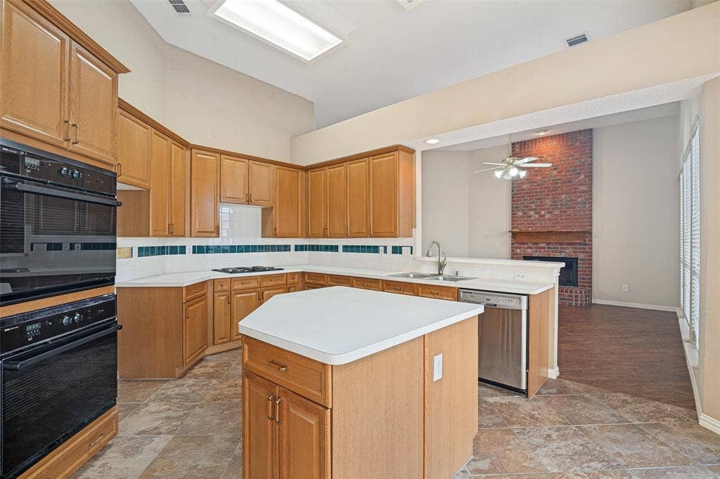 1909 Blackfoot Trail, Mesquite, TX 75149 Kitchen featuring wood cabinetry, a central island, built-in double ovens, solid-surface countertops, and tiled flooring