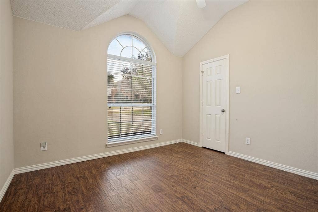 1909 Blackfoot Trail, Mesquite, TX 75149 Vaulted ceilings featuring an arched window, wood-finish flooring, and a six-panel door