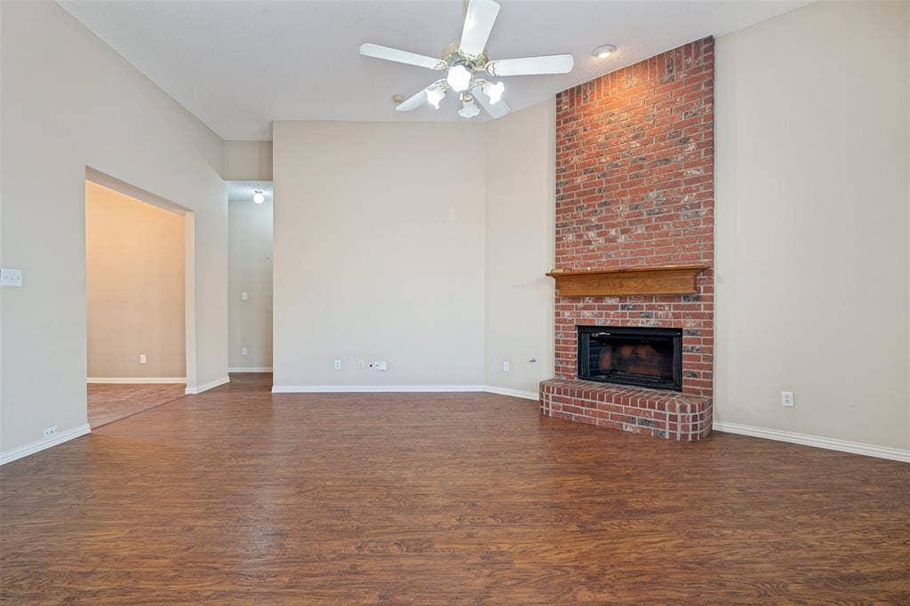 1909 Blackfoot Trail, Mesquite, TX 75149 Vaulted ceilings featuring a ceiling fan, wood-finish flooring, and a floor-to-ceiling brick fireplace with a wood mantel