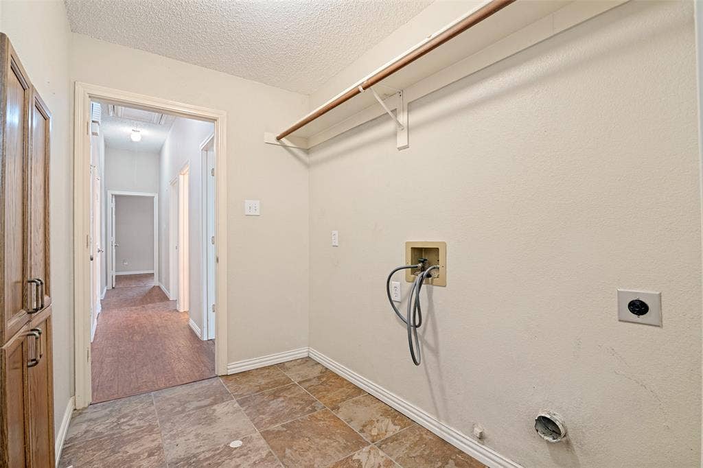 1909 Blackfoot Trail, Mesquite, TX 75149 Utility area featuring tile flooring, built-in wooden cabinetry, and overhead shelving with a hanging rod