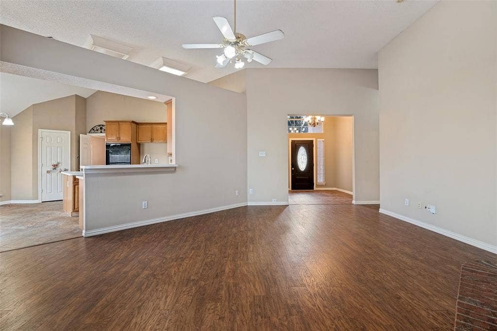 1909 Blackfoot Trail, Mesquite, TX 75149 Open concept interior featuring vaulted ceilings, wood-finish flooring, a ceiling fan with integrated lighting, and a breakfast bar