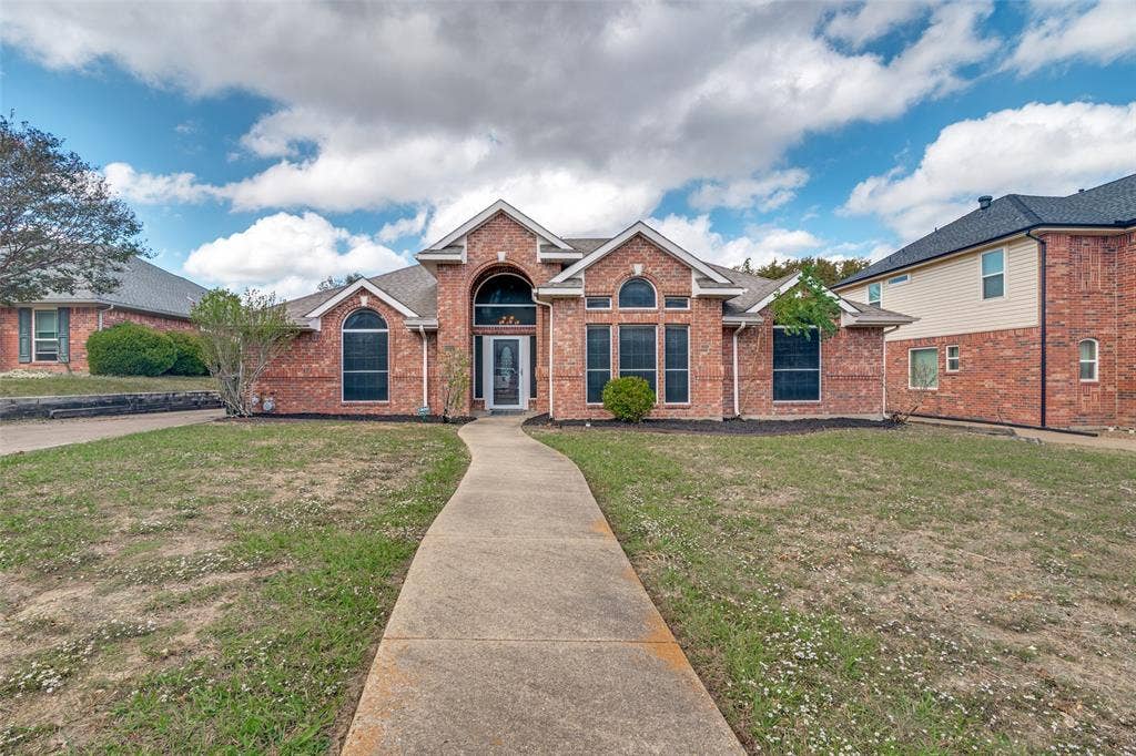 1909 Blackfoot Trail, Mesquite, TX 75149 Brick exterior featuring a gabled roofline, arched entryway, multi-paned windows, and a concrete walkway