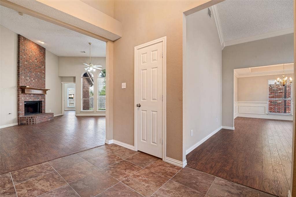 1909 Blackfoot Trail, Mesquite, TX 75149 Foyer featuring tile flooring, vaulted ceilings, and a floor-to-ceiling brick fireplace with a wood mantel