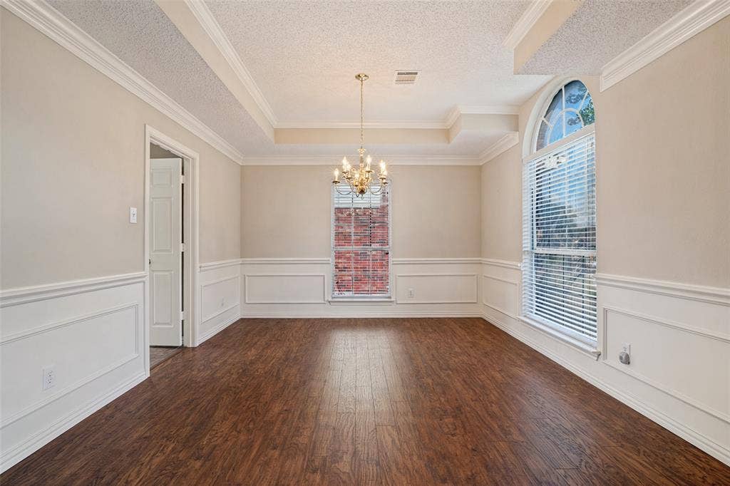 1909 Blackfoot Trail, Mesquite, TX 75149 Room featuring wood-finish flooring, wainscoting, a tray ceiling, an arched window, and a chandelier