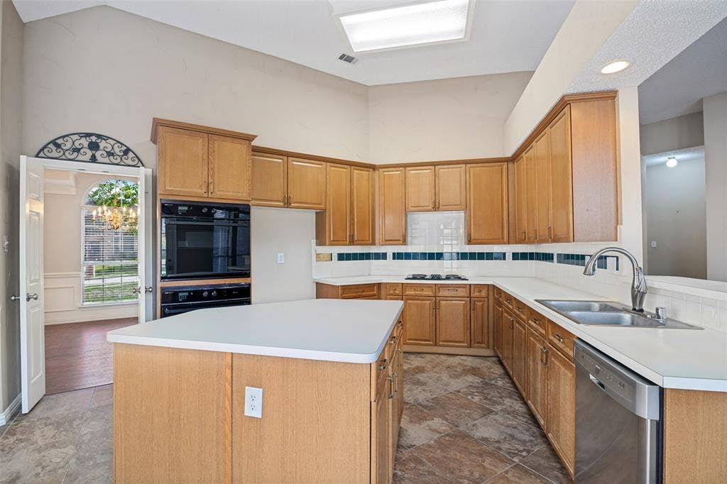 1909 Blackfoot Trail, Mesquite, TX 75149 Kitchen featuring vaulted ceilings, wood cabinetry, built-in double oven, center island, and stone-finish tile flooring